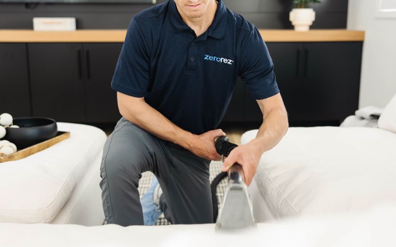 Zerorez employee cleaning a white couch.
